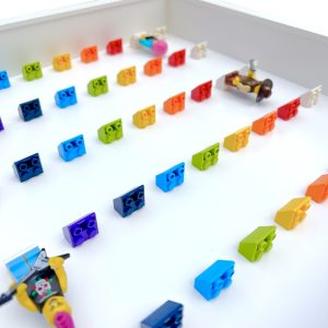 LEGO minifigure display frame case for 50 minifigures, white frame and rainbow bricks, depth view with minifigures